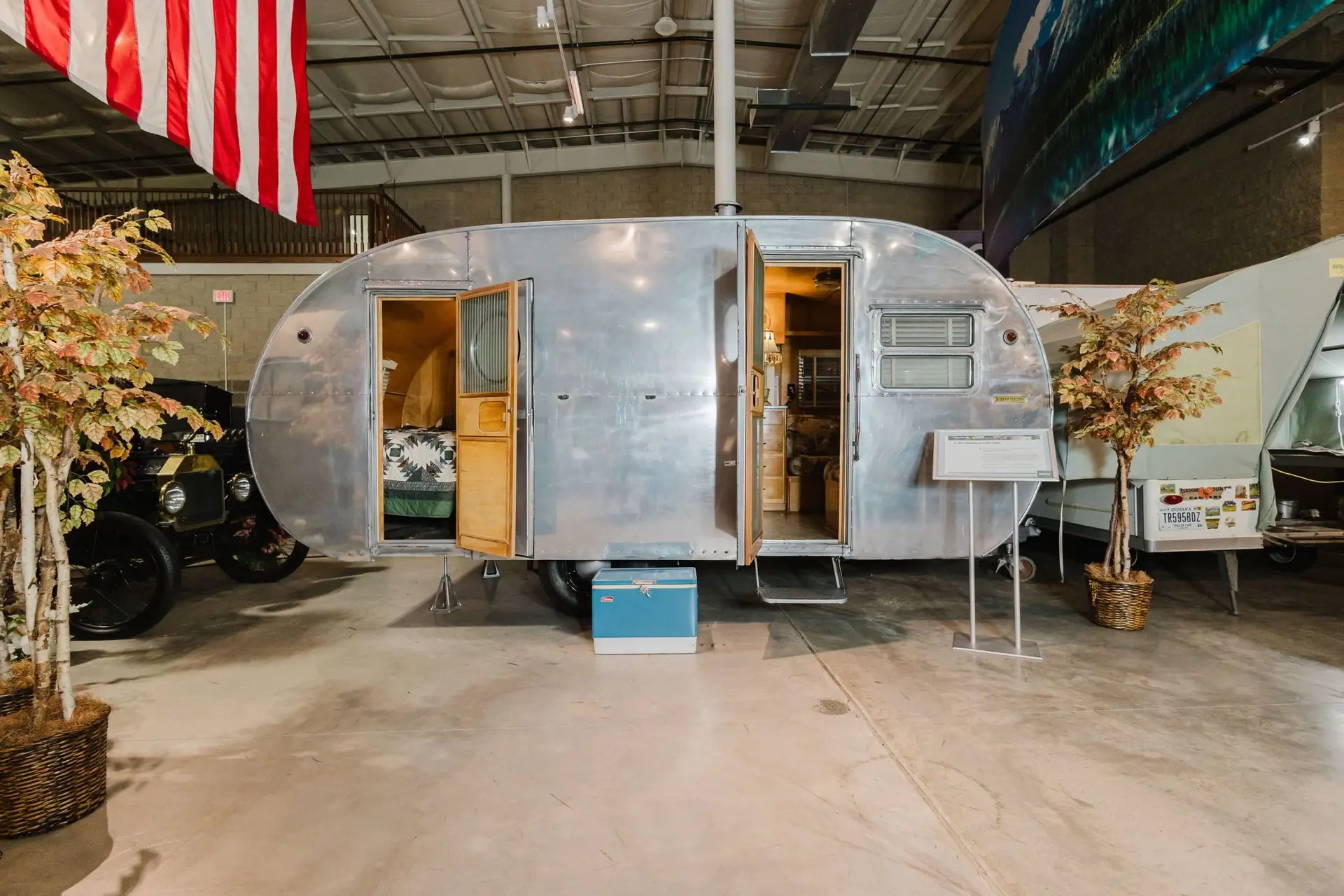 Polished aluminum vintage travel trailer exhibit inside the RV/MH Hall of Fame & Museum.