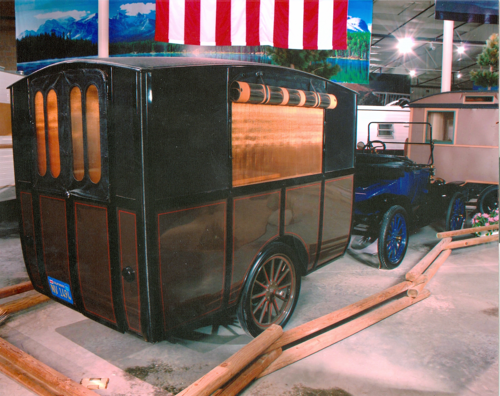 1913 Earl Travel Trailer parked next to a vintage Model T Ford inside a museum.